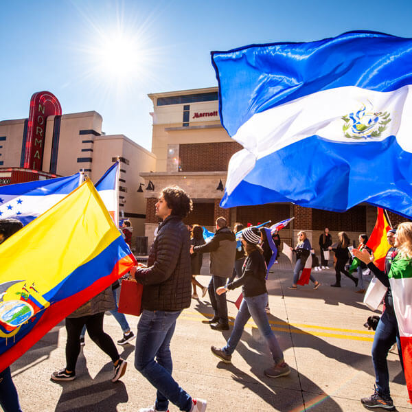 International Studies students walk in the Labor Day parade holding their countries' flag.